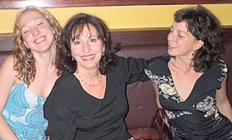 Jenna, Linda & Kate sitting on bench seat at a restaurant. Linda their mother is beaming and the two girls, both beautiful -- one blonde and one brunett -- are posing with their eyes closed.