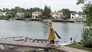 A view of the harbor with a little fisherman weathervane plus beautiful blue water and picturesque homes surrounding the inlet.