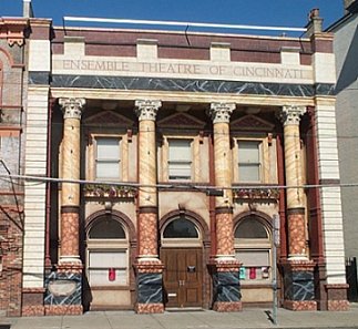 Pictured: the front of Ensemble Theatre of Cincinnati features tall multi-colored pillars and a large bank-like logo chiseled in stone across the top.