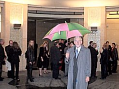 Jimmy standing in stairwell with pink and green umbrella.