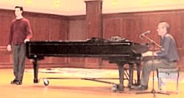 11 foot grand piano. Steve playing and a slender young man stands at the end singing.