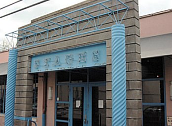 The outside facade of Stages Theatre. It has poweder blue curlicue poles and a neon sign.