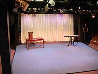 The stage with Jimmy's wooden table and high-backed chair on one side. My keyboard on the other. Behind us is a white curtain. Stretching before us is a blue carpet.